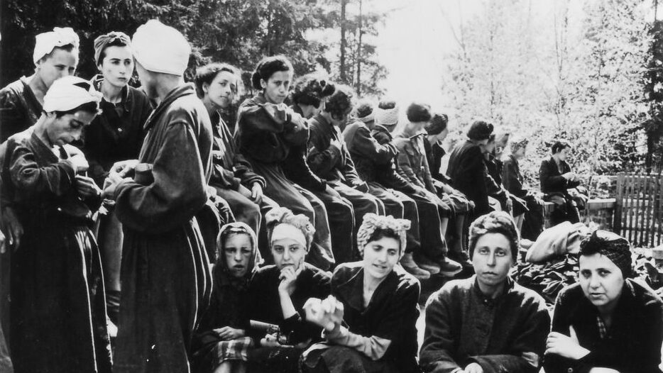 Überlebende Frauen des befreiten Außenlagers Penig sitzen und stehen auf einem Hof hinter dem Gebäude des ehemaligen Luftwaffenlazaretts Altenburg. (Foto: David E. Scherman, © Gedenkstätte Buchenwald)